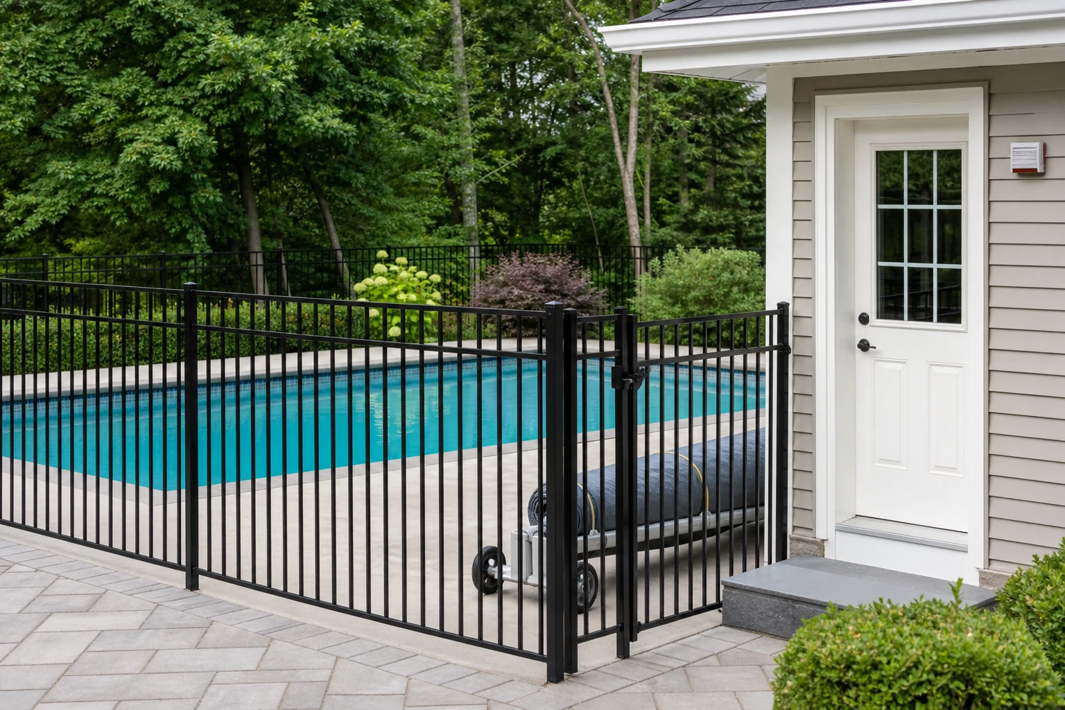 A residential pool protected by a fence, self-latching gate, door alarm, and safety cover